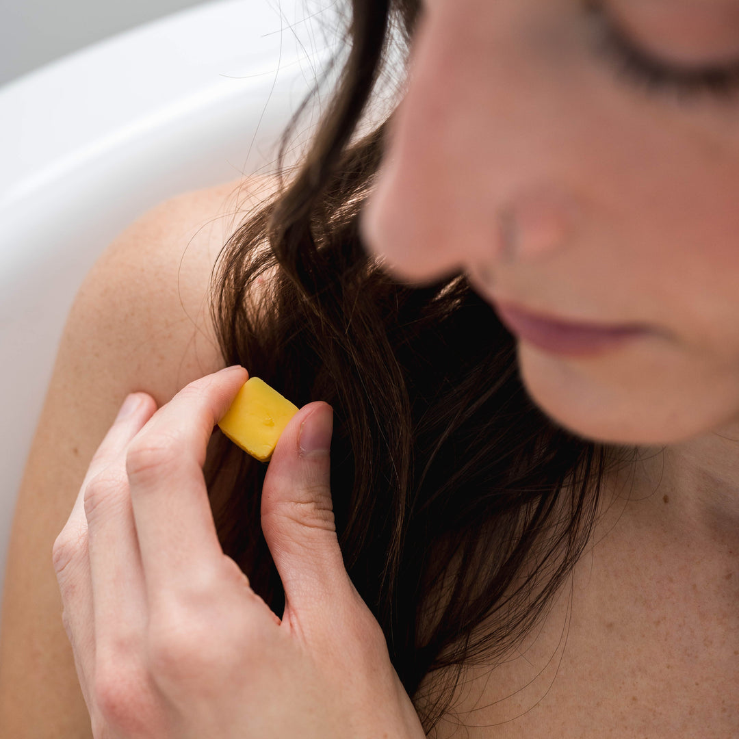 Woman holding eco-friendly conditioner tablet that's sustainable and dissolves in water. Clean beauty conditioner tablets that are plastic-free and waterless. Conditioner pods that are natural and travel-friendly.
